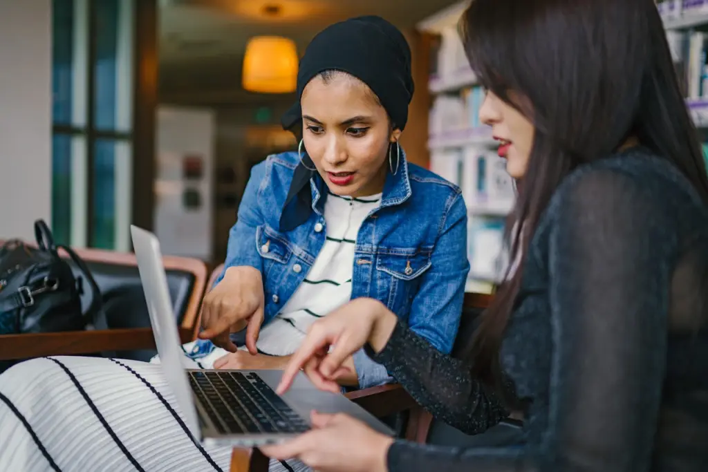 Two females speaking about details on a laptop